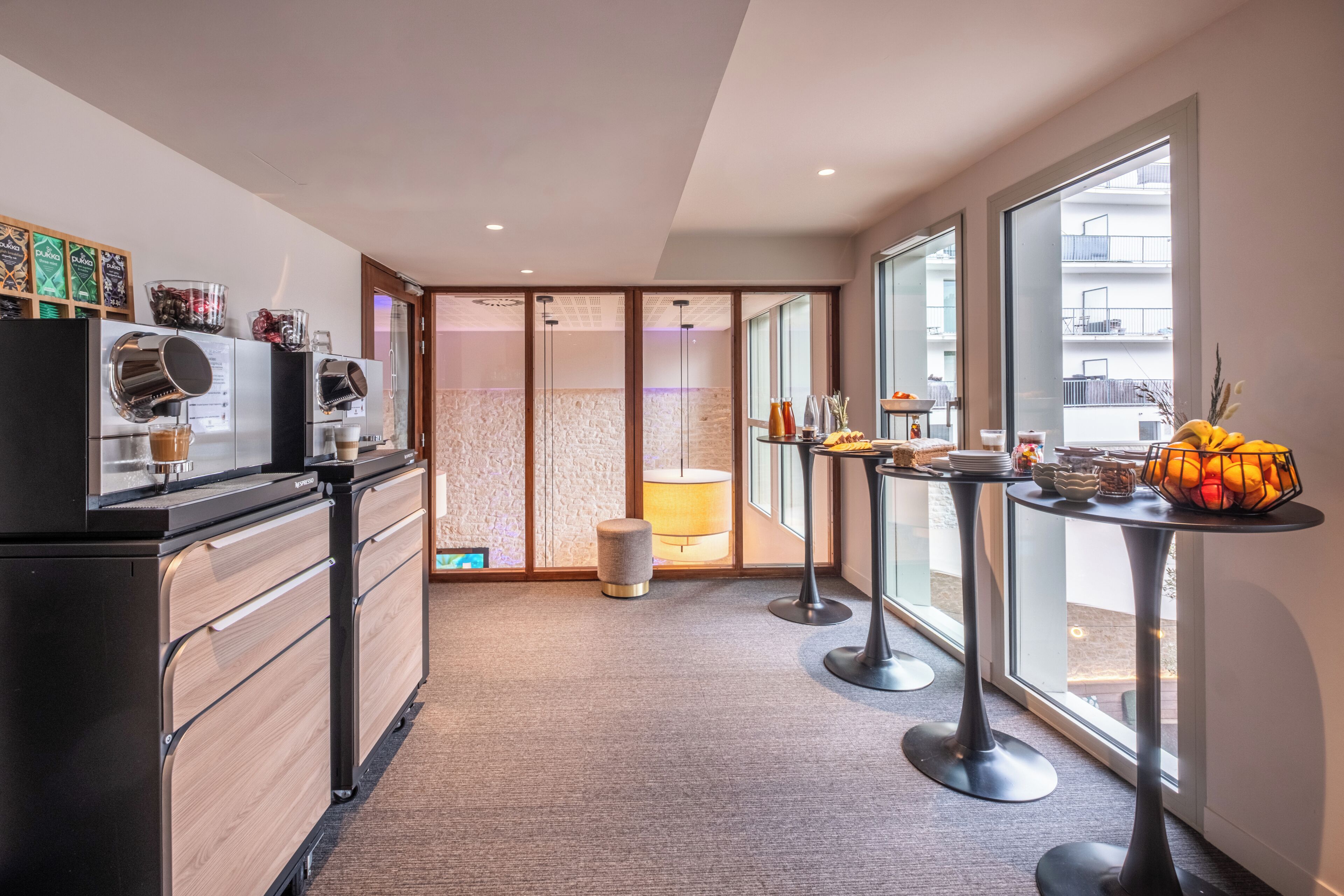 Een moderne keuken met een ingebouwde espressomachine, een koffiehoek en een stadszicht door grote ramen.