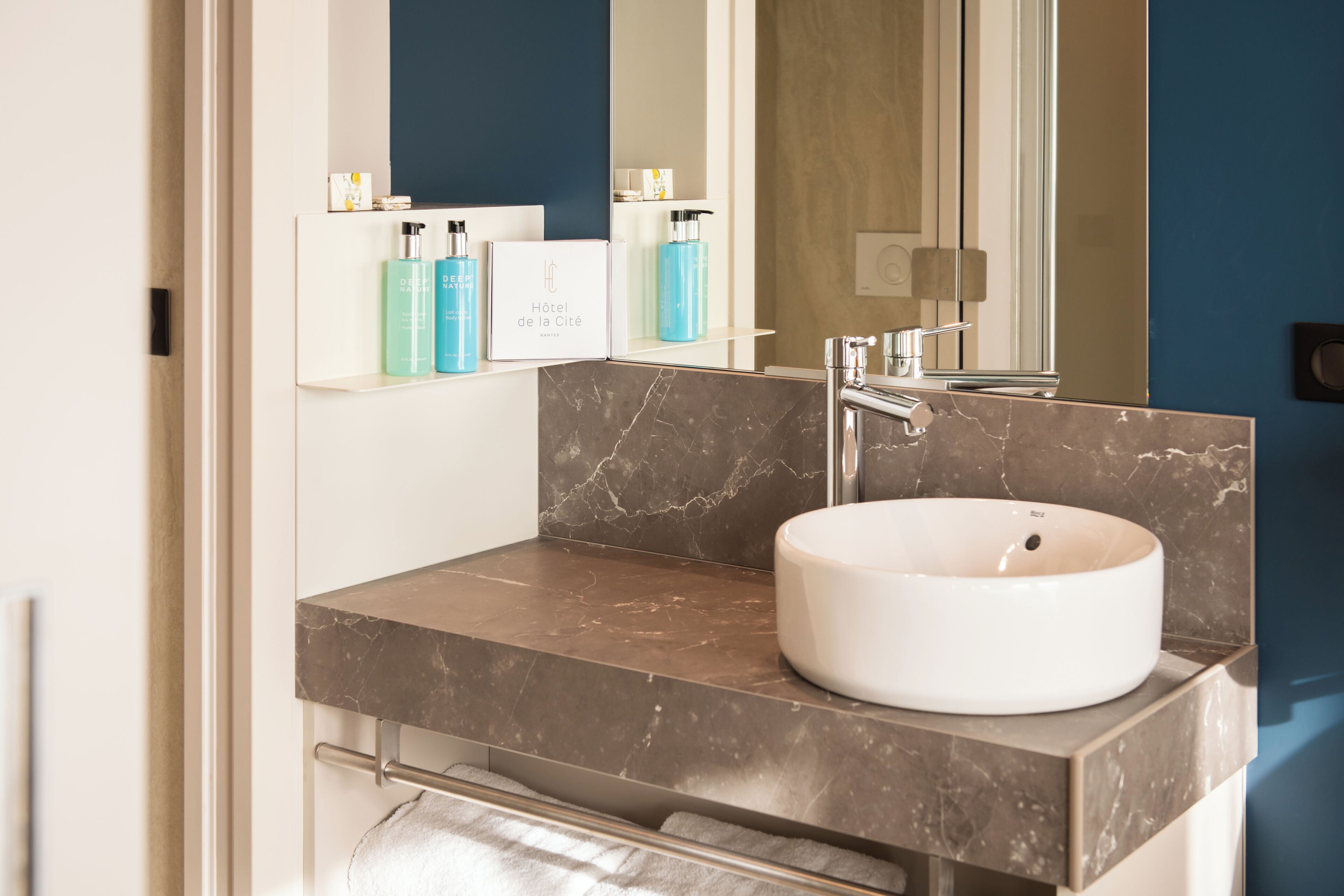 A modern bathroom with a marble countertop, a white sink, and a mirror above it.