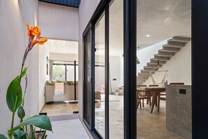 Un interno moderno con una scala, una zona pranzo e una vista attraverso una porta in vetro.