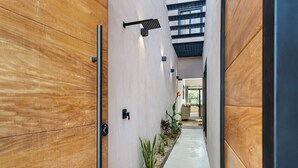 A modern hallway with wooden paneling, a black door, and a small plant arrangement. - Quiet La Punta Surf Villa (Santa María Colotepec)