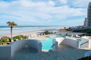 Área de piscina do resort com vista para a praia e oceano.
