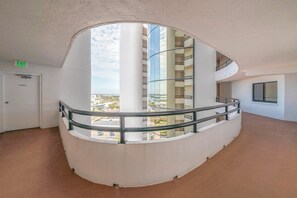 En buet balkon med gelænder af glas med udsigt over bybilledet.