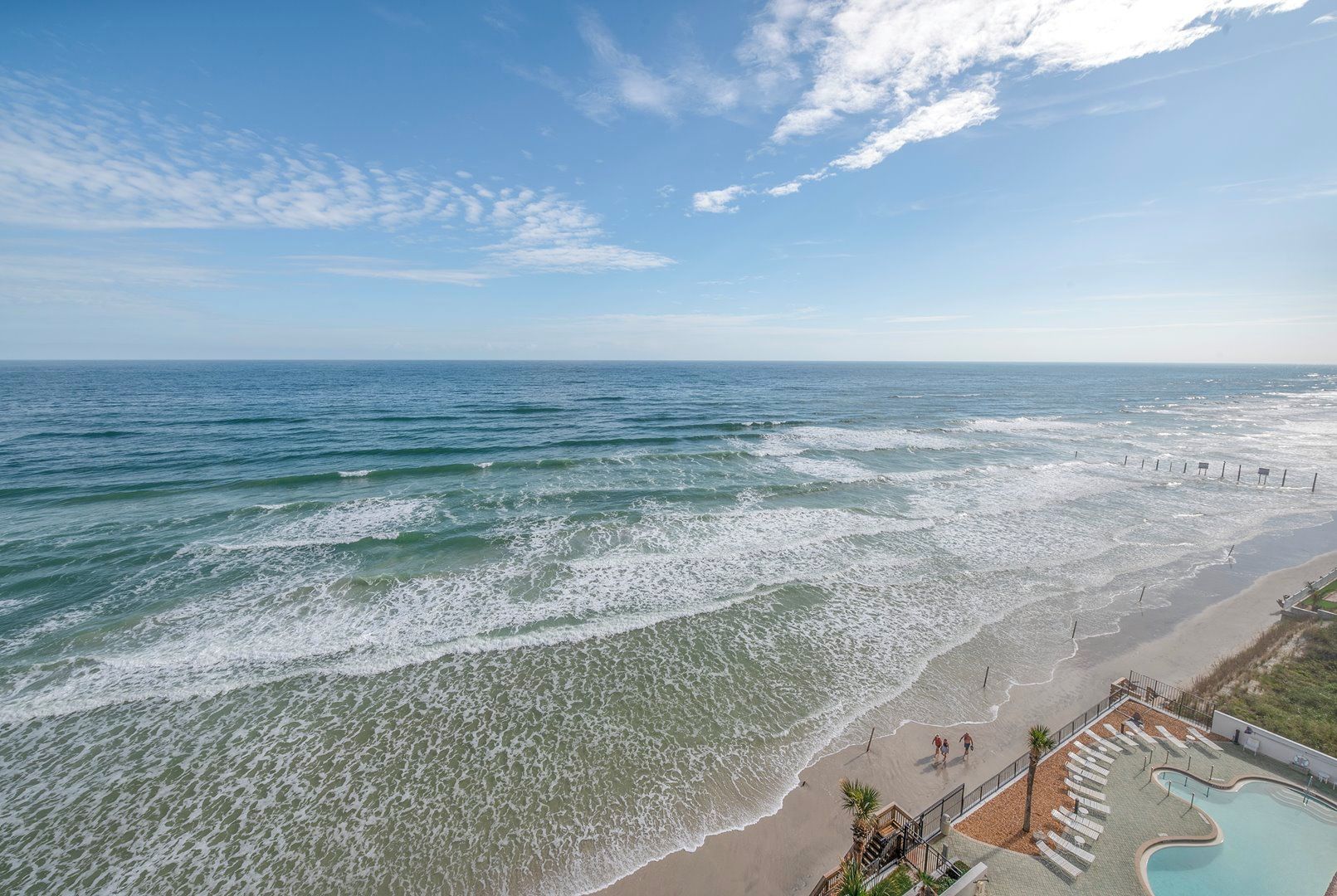 A beach with waves, a pool, and a walkway.