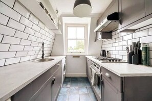 Features a clean design with white subway tiles, a light-colored countertop, and a window for natural light.