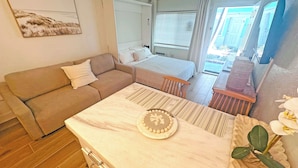 Une pièce confortable comprenant un lit, un canapé, une table à manger et un petit coin cuisine.