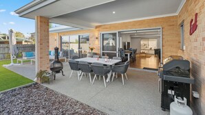 Eine Terrasse im Freien mit Tisch, Stühlen, einem Grill und einer Barbecue-Einrichtung.