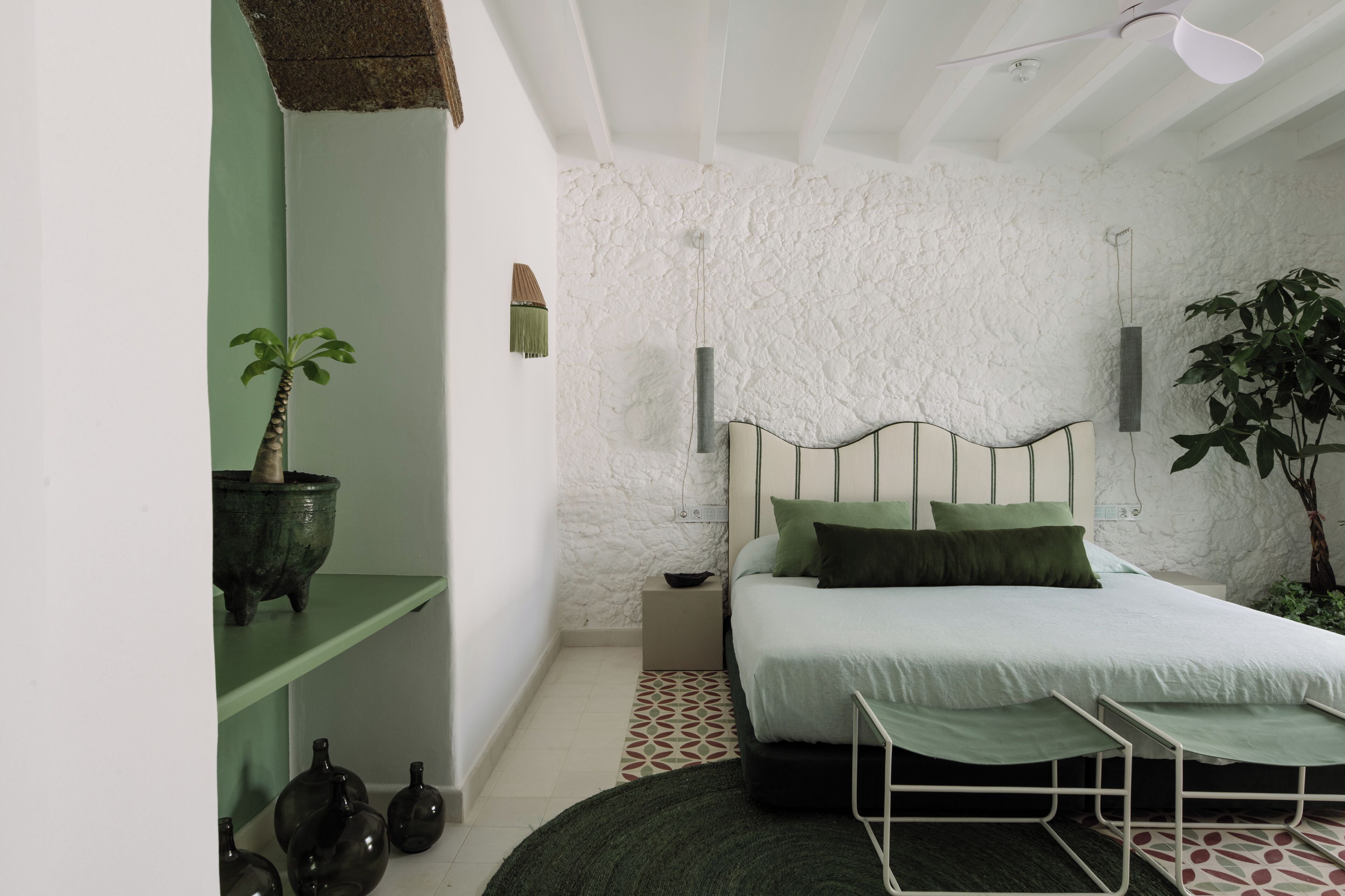 Ein Schlafzimmer mit einem Bett, einem Nachttisch und einer Zimmerpflanze.