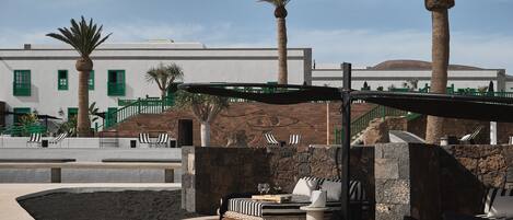 A rooftop lounge area with outdoor seating, a small pool, and palm trees.