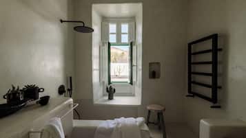 Un baño con bañera, ventana con vistas, toallero y ducha.