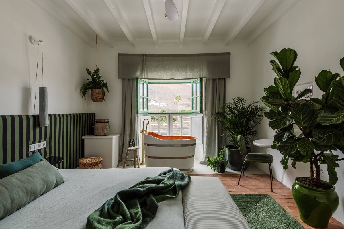 Un dormitorio moderno con una cama grande, una bañera y vistas al exterior.