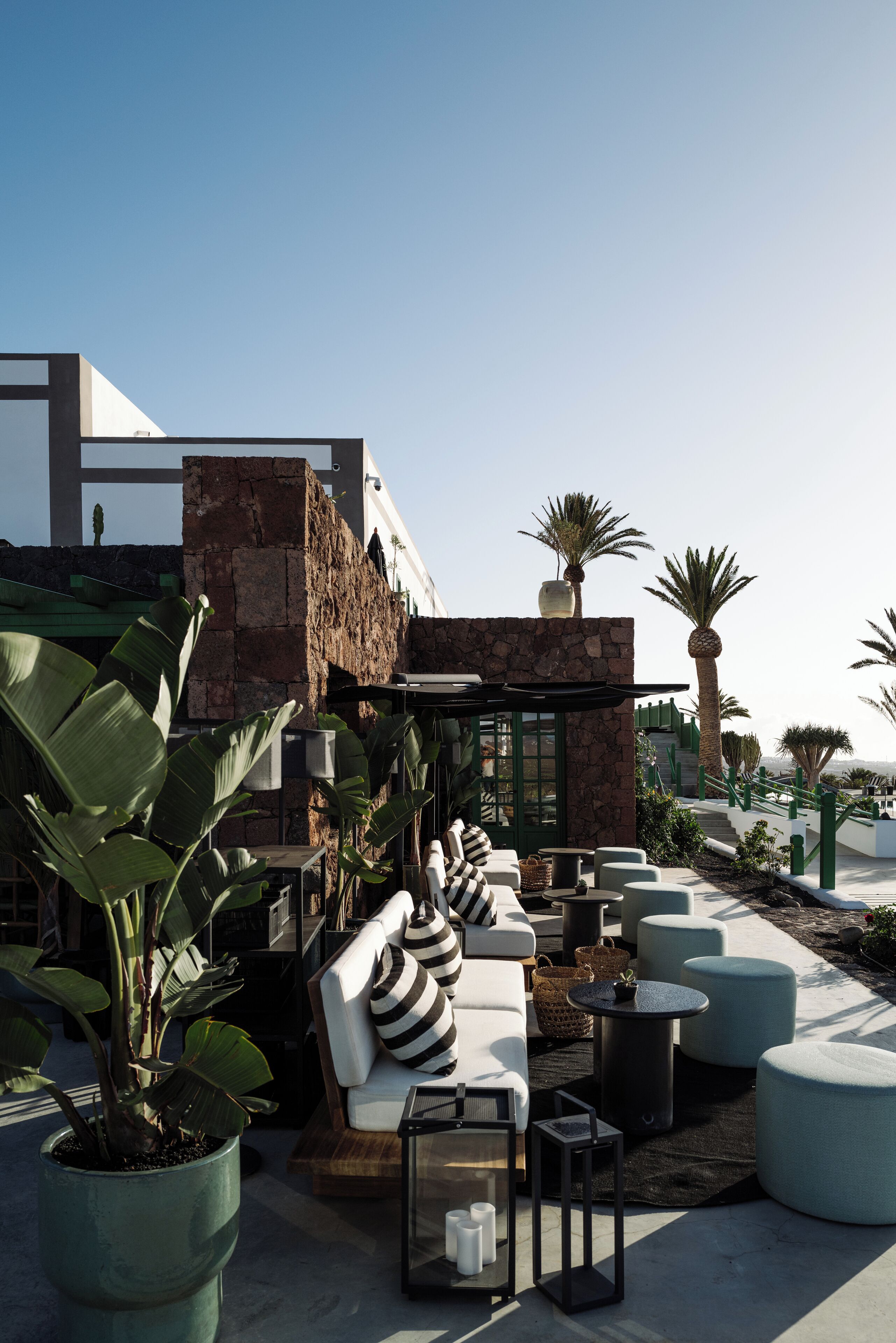 An outdoor seating area with modern furniture, a stone wall, and potted plants.