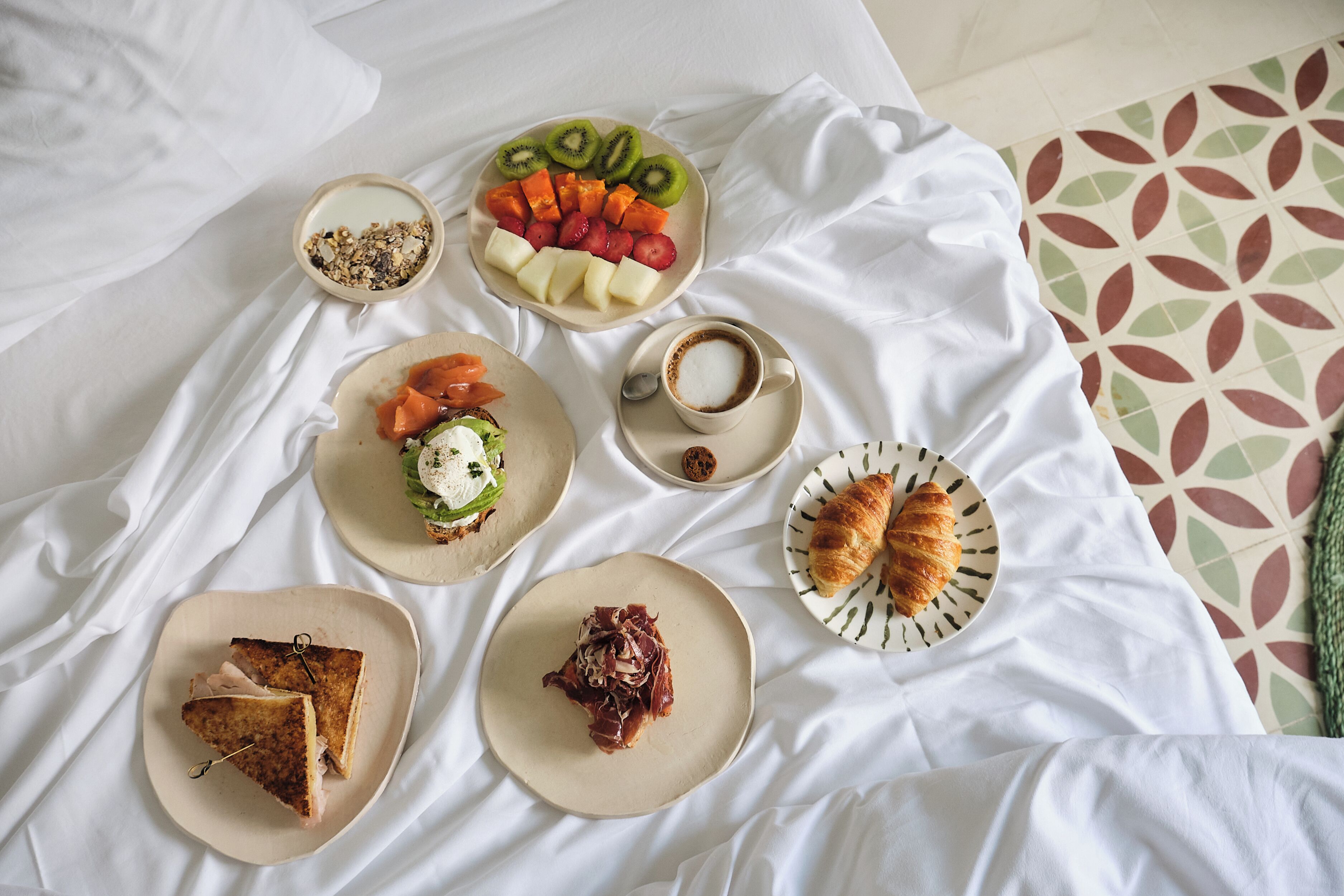 Uma mesa de café da manhã com diversas opções de comida, incluindo frutas, um croissant e um sanduíche.