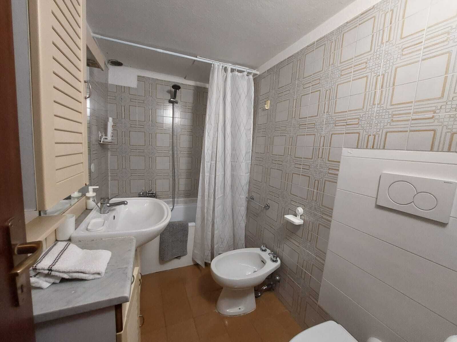 A bathroom with a sink, bidet, toilet, and shower.
