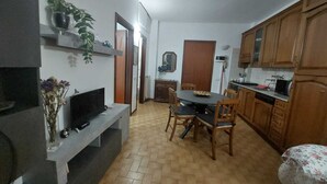 Ein kompakter Wohnbereich mit Essplatz, Küche und Fernseher auf einem Standfuß.