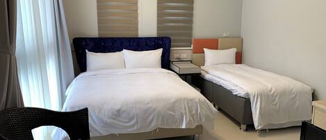 A hotel room with a large bed, a smaller bed, a desk, and a chair.