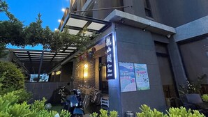 Un edificio moderno con un acceso cubierto y un letrero que indica un restaurante.