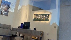Una sala de estar moderna con techo alto, una araña, una zona de comedor con mesa y sillas, y obras de arte en las paredes.