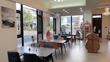 Interior moderno de restaurante com mesas e cadeiras, janelas amplas e um telefone público antigo.