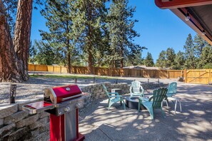 An outdoor patio with a barbecue grill, green Adirondack chairs, and a stone fire pit. - New Listing! Bend Home ~ Hot Tub ~ Dog Friendly (Bend)