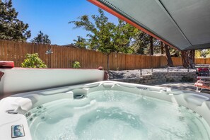 A hot tub area with a wooden fence, a stone wall, and a tree. - New Listing! Bend Home ~ Hot Tub ~ Dog Friendly (Bend)