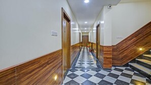Un pasillo de hotel con paneles de madera, suelo de cuadros y una escalera con barandilla de madera.