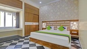 Habitación de hotel con una cama grande, armario de madera y un papel tapiz estampado.
