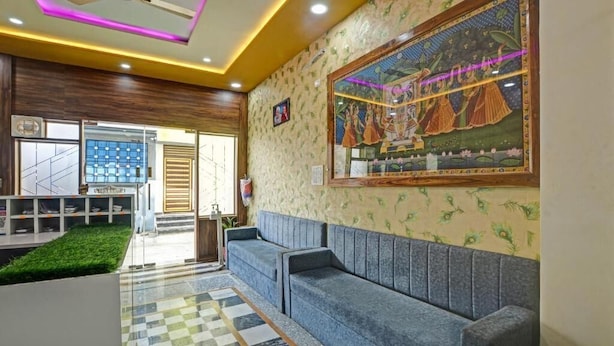 Un vestíbulo moderno con piso a cuadros, un sofá azul y un gran mural en la pared.