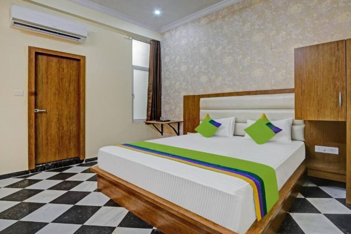A hotel room with a bed, wooden wardrobe, and a checkered floor.