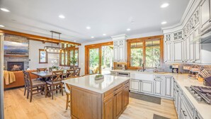 A spacious kitchen with wooden cabinetry, a large island, and a dining area with a fireplace. - Family Time Comes First | Stay Longer w/ 1PM In/Out Benefits (Cle Elum)