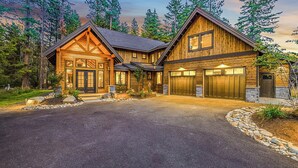 A two-story log cabin with a stone driveway, surrounded by trees. - Family Time Comes First | Stay Longer w/ 1PM In/Out Benefits (Cle Elum)