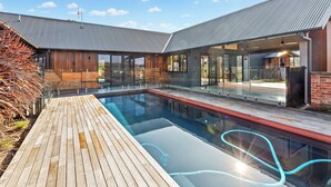 A modern house with a swimming pool, wooden deck, and glass doors leading to the interior. - Buller Peeps  - Mansfield (Mansfield)