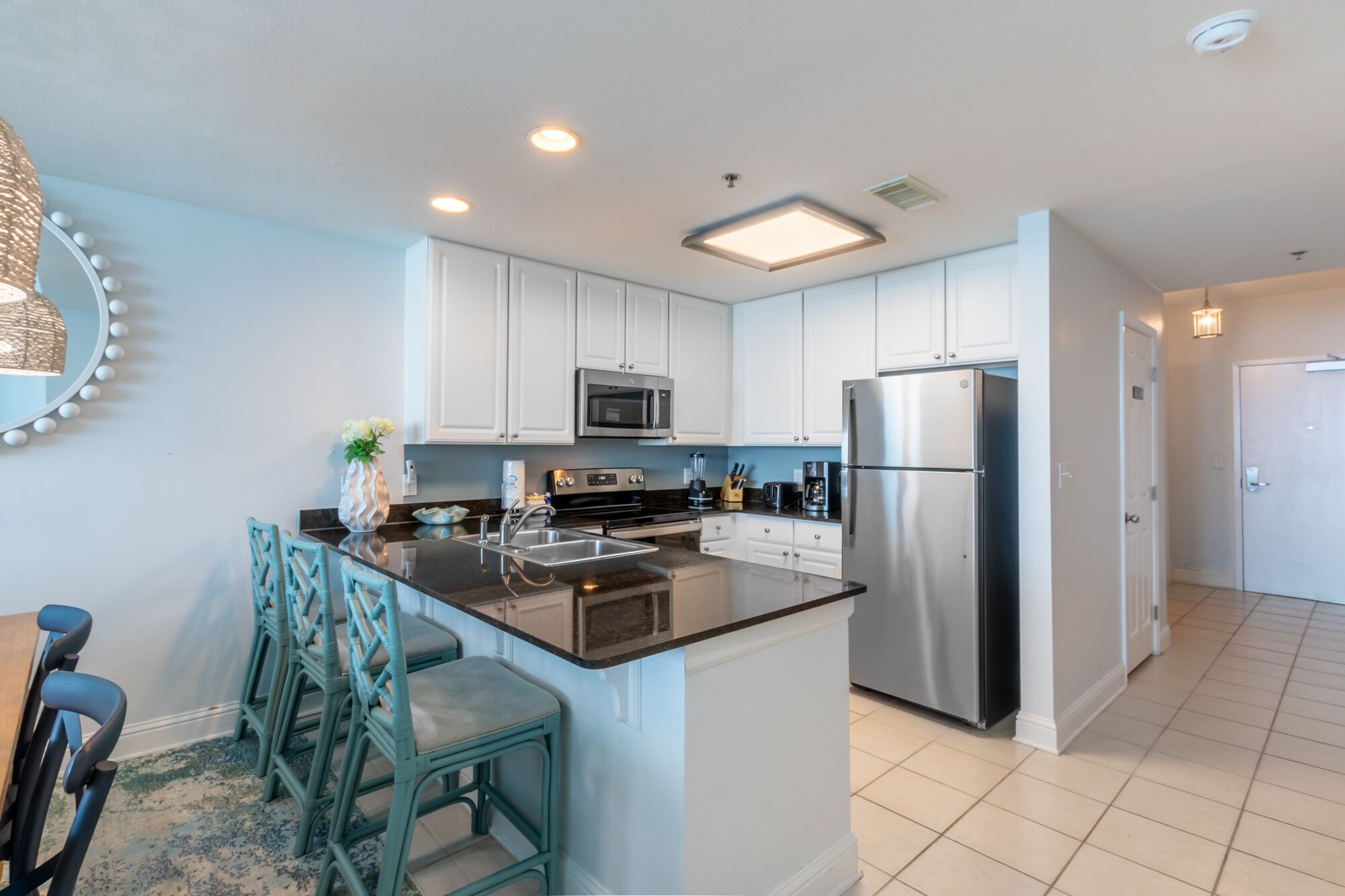 A modern kitchen with white cabinets, stainless steel appliances, and a central island with bar stools.