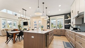 A modern kitchen with a central island, wooden cabinets, and pendant lighting. - Bighorn & Bluebell at Chelan Lookout Vacation Rentals (Chelan)