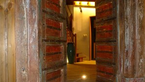 Une porte en bois, au style rustique, donne sur un couloir doté d’un plancher en bois et d’un banc.