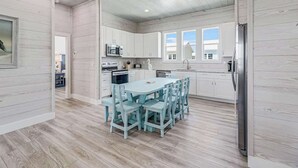 Una cocina moderna con armarios blancos, una isla central y un comedor con sillas a juego.