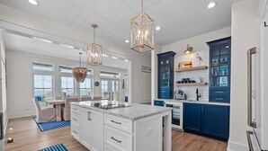 Una cucina moderna con mobili bianchi, un'isola centrale e tocchi di blu.