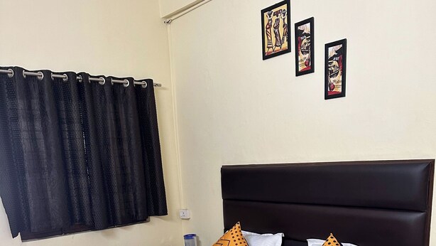 Una cama con una colcha estampada, dos almohadas con lunares y un cabecero oscuro.