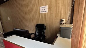 Un mostrador de recepción con un panel de madera, una silla de cuero negro y una impresora HP.