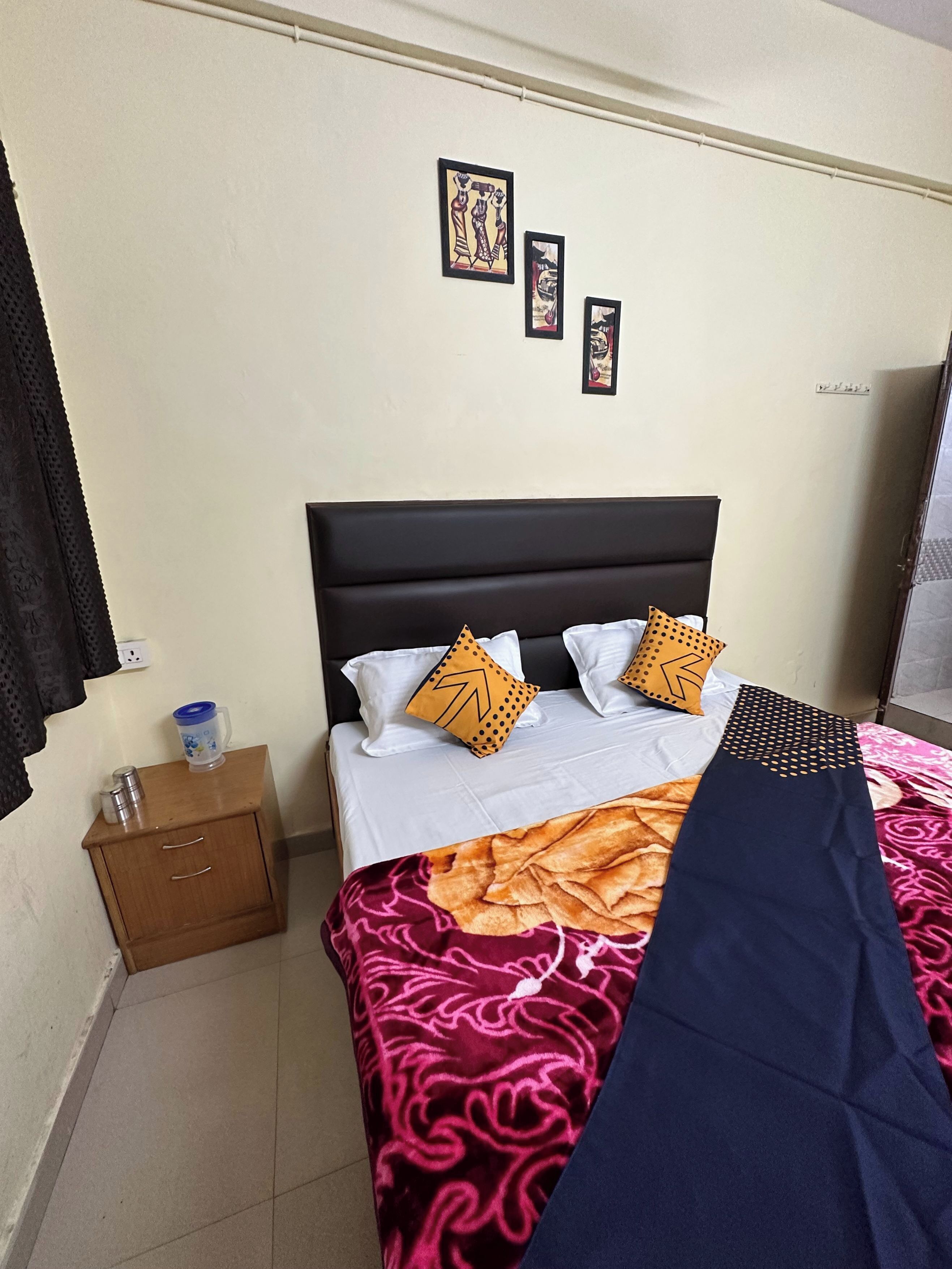 A neatly made bed with patterned bedding, a bedside table with a lamp, and wall-mounted artwork.