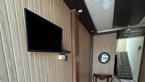 Un pasillo con piso estampado, un televisor montado y una escalera al fondo.