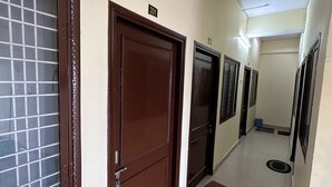 Un pasillo con puertas numeradas 201 y 202, una cámara de seguridad y un cubo azul en el suelo.