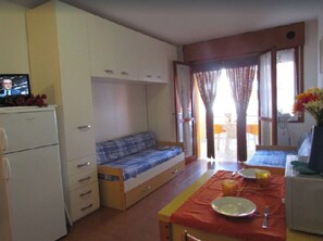 Une pièce de taille modeste comprenant un lit, une petite kitchenette et un coin repas.
