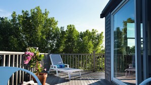 Une terrasse en bois avec un fauteuil de jardin blanc et une plante en pot.