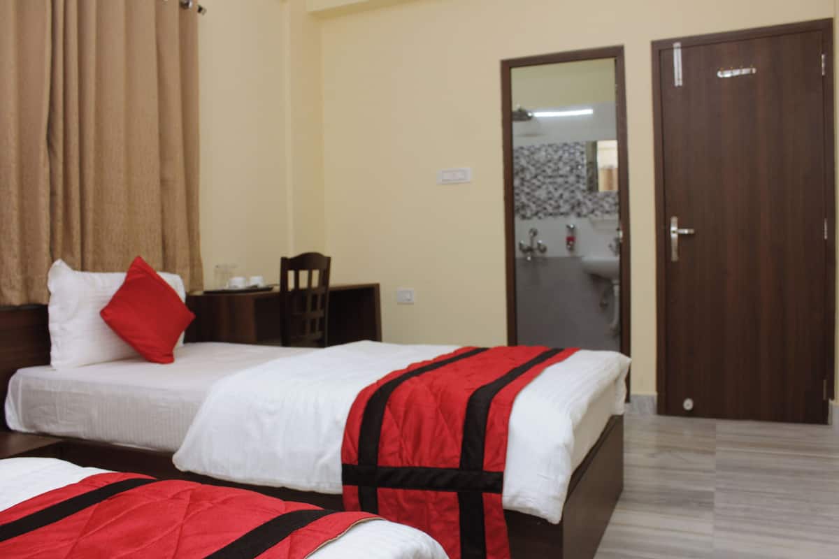 A hotel room with two beds, a wooden headboard, a red pillow, a white pillow, a mirror, and a door.