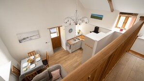A spacious loft-style apartment with a dining area, kitchen, and a balcony.