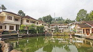 Ein friedlicher Innenhof mit Teich, Steinstufen und traditionellen Gebäuden mit Balkonen.