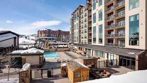 Un hôtel doté d’une piscine, d’un espace extérieur aménagé et offrant une vue sur une station de ski en arrière-plan.
