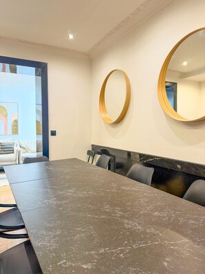 A conference room with a long table, chairs, and two wall-mounted mirrors.