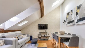 A modern living room with a sofa, coffee table, and dining area with chairs and a table. - Urban Flat  117 - Charming 3BDR Apartment in Paris (París)