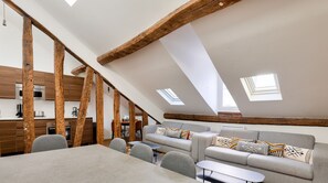 Habitación estilo loft con zona de comedor, sofá y cocina al fondo.
